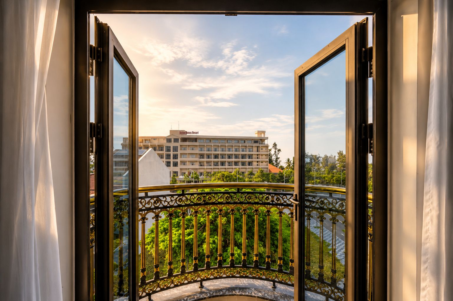 An open balcony with a wrought iron railing, a view of a hotel building, and a clear sky.
