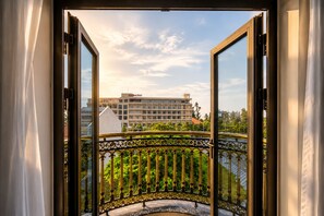 Un balcon ouvert avec une balustrade en fer forgé, une vue sur un immeuble d’hôtel et un ciel dégagé.