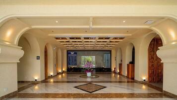 A hotel lobby with a marble floor, wooden reception desk, and a sign indicating the location of the restrooms.