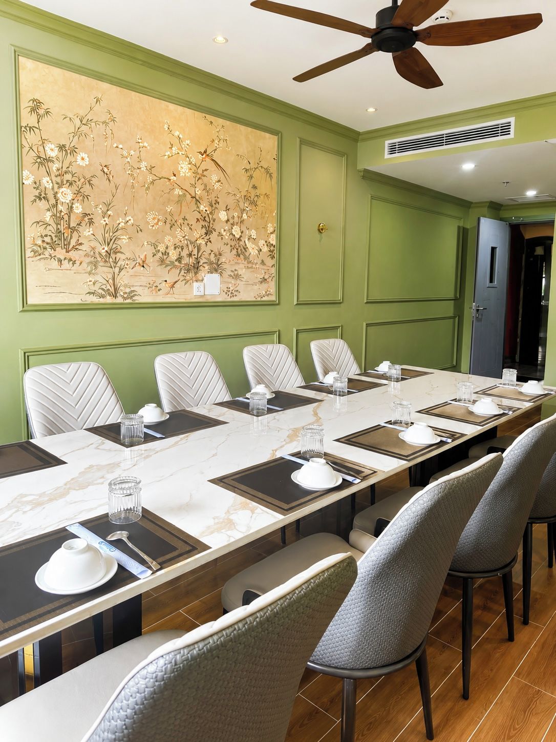 A conference room with a long table, chairs, and a ceiling fan.