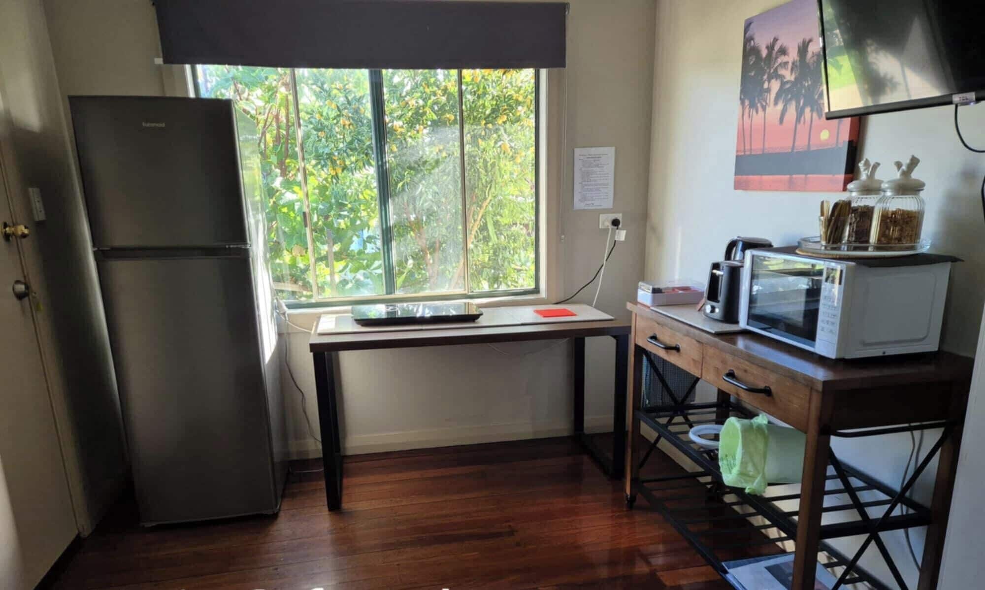 Cocina compacta con refrigerador, microondas y una pequeña encimera.