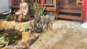 A covered porch with a Buddha statue, a small pond, and a seating area with chairs. - Bunbury's Most Convenient Location (Carey Park)