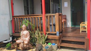 A covered porch with a Buddha statue, a small pond, and a seating area with chairs. - Bunbury's Most Convenient Location (Carey Park)