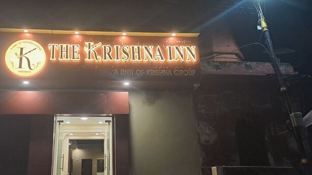 The exterior of The Krishna Inn, a unit of the Krishna Group, with a prominent illuminated sign and a doorway leading into the building. - The Krishna Inn (Varanasi)