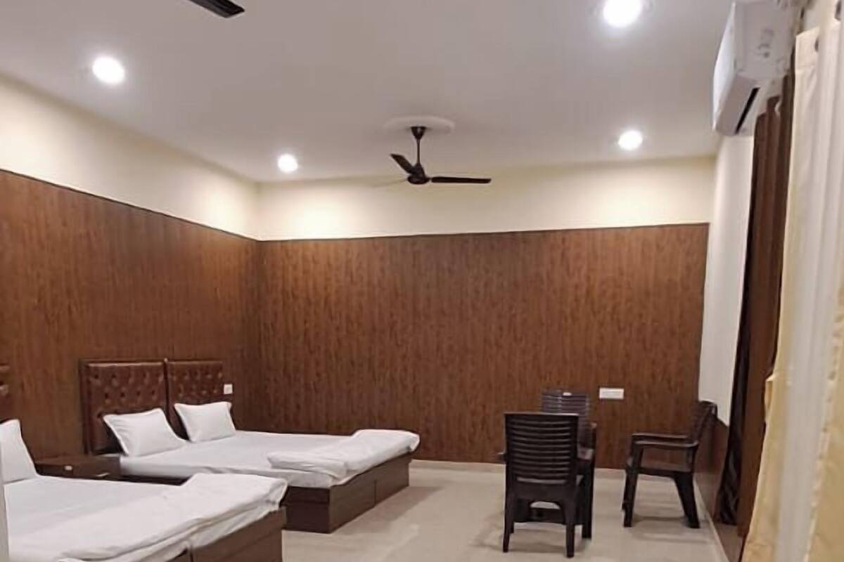 A hotel room with two beds, a ceiling fan, and a small table with chairs.