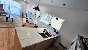 A modern kitchen with a marble countertop, wooden cabinets, and a built-in sink.