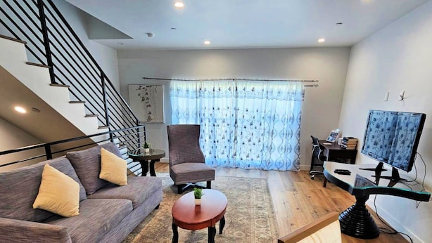 A modern living room with a sofa, armchair, coffee table, and a TV.