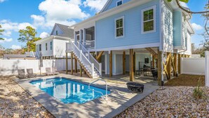 A two-story house with a pool, outdoor seating, and a covered patio area. - New Elevated Home | Pool | 6-Seater Golf Cart (Oak Island)
