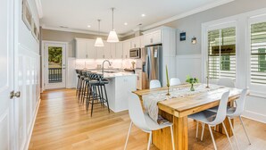 A modern kitchen with white cabinets, a central island, and pendant lighting. - New Elevated Home | Pool | 6-Seater Golf Cart (Oak Island)