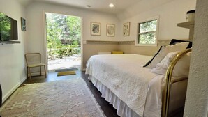 Un dormitorio con una cama grande, una silla, una alfombra y una ventana.