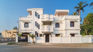 A multi-story white building with balconies, a gated entrance, and a sign indicating rooms are available. - MP Villa (Vanur)
