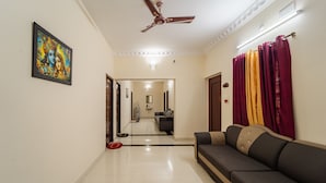 A hallway with a ceiling fan, a sofa, and a painting on the wall. - MP Villa (Vanur)