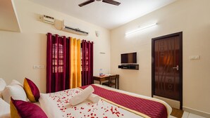 A hotel room with a bed, curtains, a television, and a door. - MP Villa (Vanur)