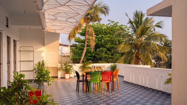 A terrace with a checkered floor, a table with chairs, potted plants, and palm trees in the background. - MP Villa (Vanur)