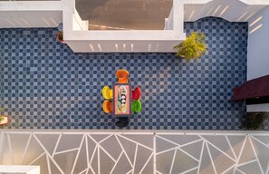 Un mur carrelé de carreaux bleus et blancs formant un motif à carreaux, avec une table et des chaises au centre.