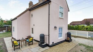 A pink house with a patio, a table, chairs, and a water tank.