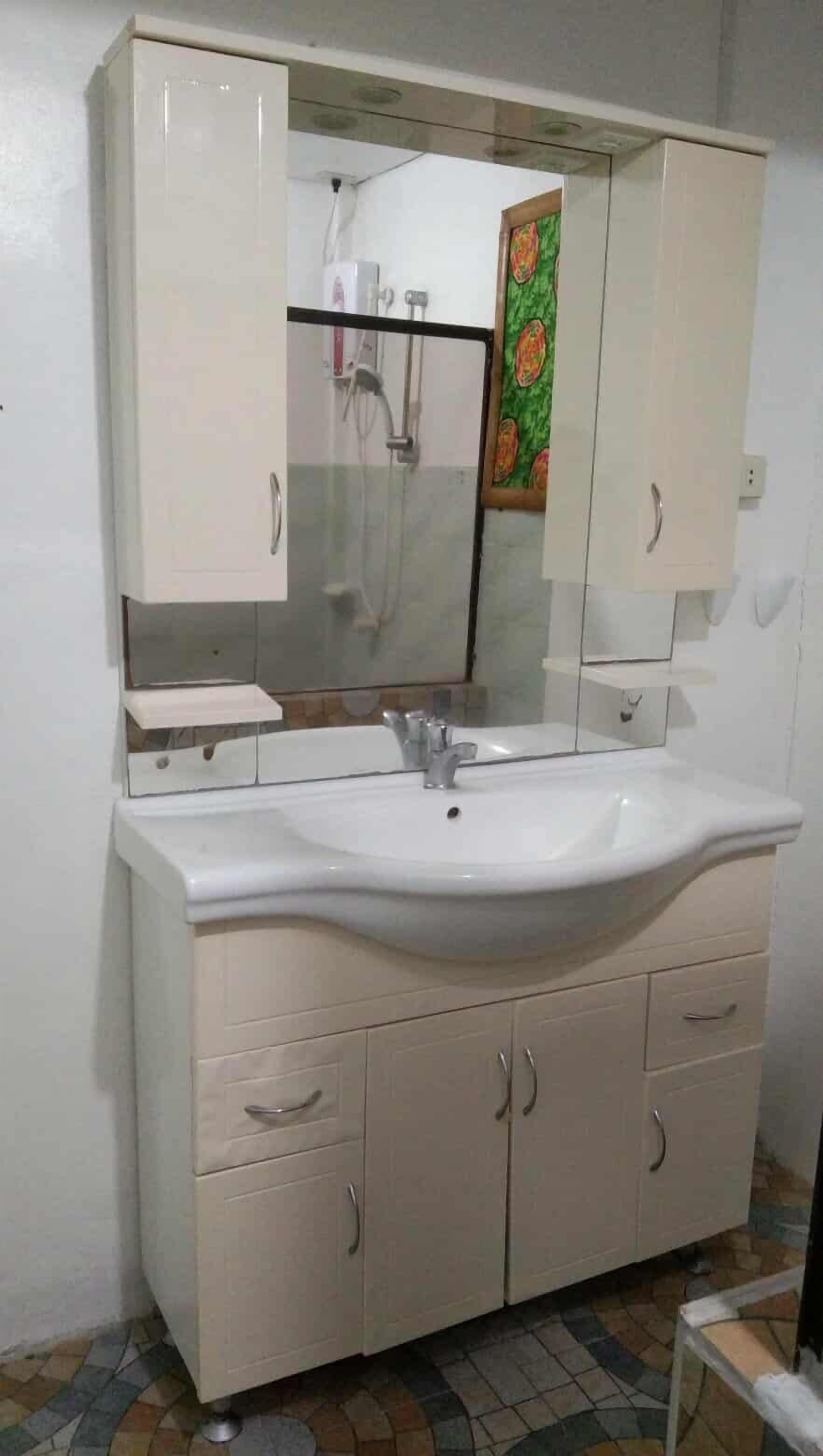 Une salle de bain avec un lavabo blanc, un miroir et des meubles de couleur beige.