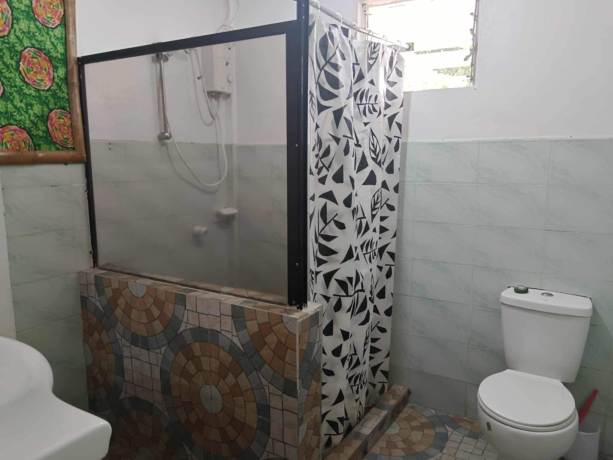 A bathroom with a shower enclosure, a toilet, and a tiled floor.