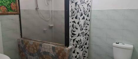 A bathroom with a shower enclosure, a toilet, and a tiled floor.