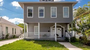 A two-story house with a front porch, a small attached garage, and a clear sky. - Spacious 3BR Sleeps 8/Perfect for Groups (San Antonio)