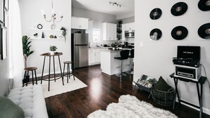 A modern kitchen with white cabinets, a stainless steel refrigerator, and a dining area with stools. - Spacious 3BR Sleeps 8/Perfect for Groups (San Antonio)