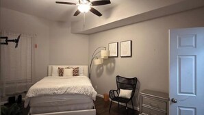A bedroom with a bed, a chair, a white door, and a ceiling fan. - Spacious 3BR Sleeps 8/Perfect for Groups (San Antonio)