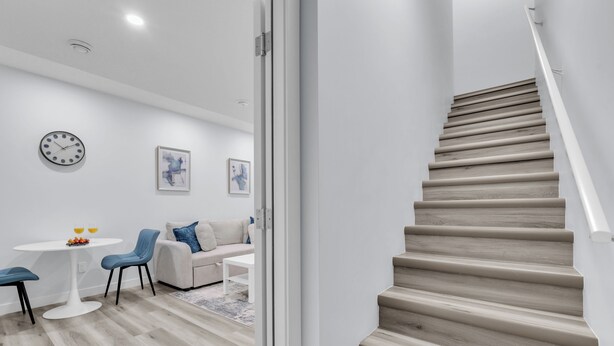 Un intérieur moderne avec un escalier, un coin repas doté d’une table ronde et un canapé.