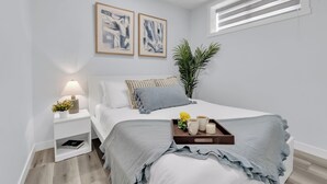 Une chambre moderne avec un lit, une table de chevet et une fenêtre avec des stores.
