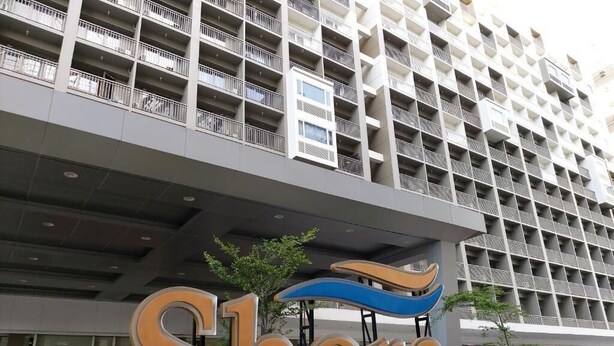 A hotel sign with the name 'Shore' and a stylized wave design. - Spacious and Cozy Condo near Mall of Asia (Pasay City)