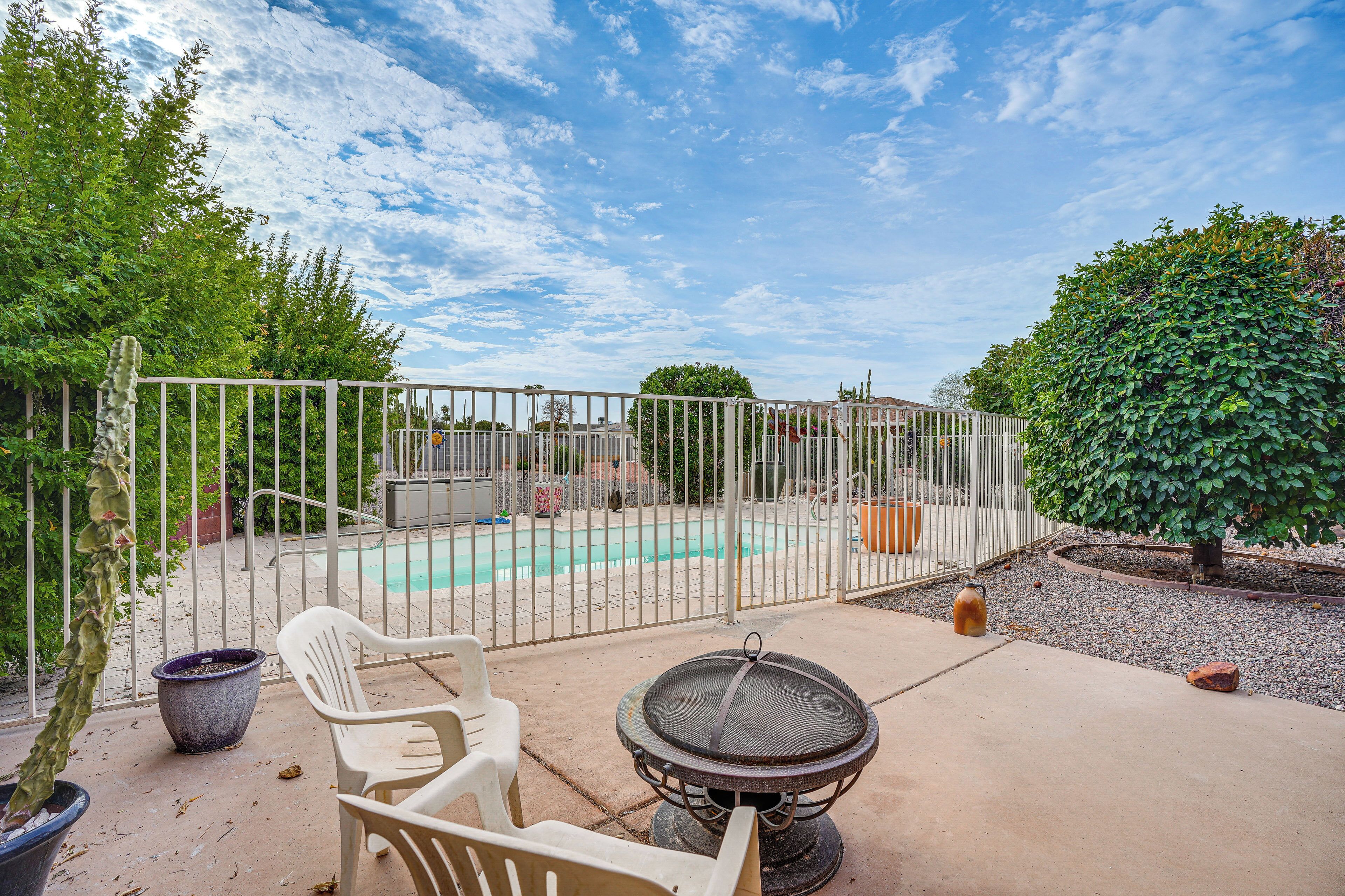 A backyard with a pool, a grill, and a fenced area.