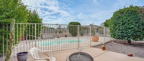 A backyard with a pool, a grill, and a fenced area.