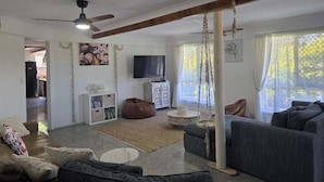 A living room with a sofa, a bean bag, a TV, and a ceiling fan. - SoKo Holiday Apartment (Agnes Water)
