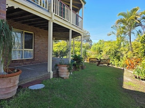 A two-story house with a covered porch, brick exterior, and a well-maintained garden with various plants and a wooden fence.
