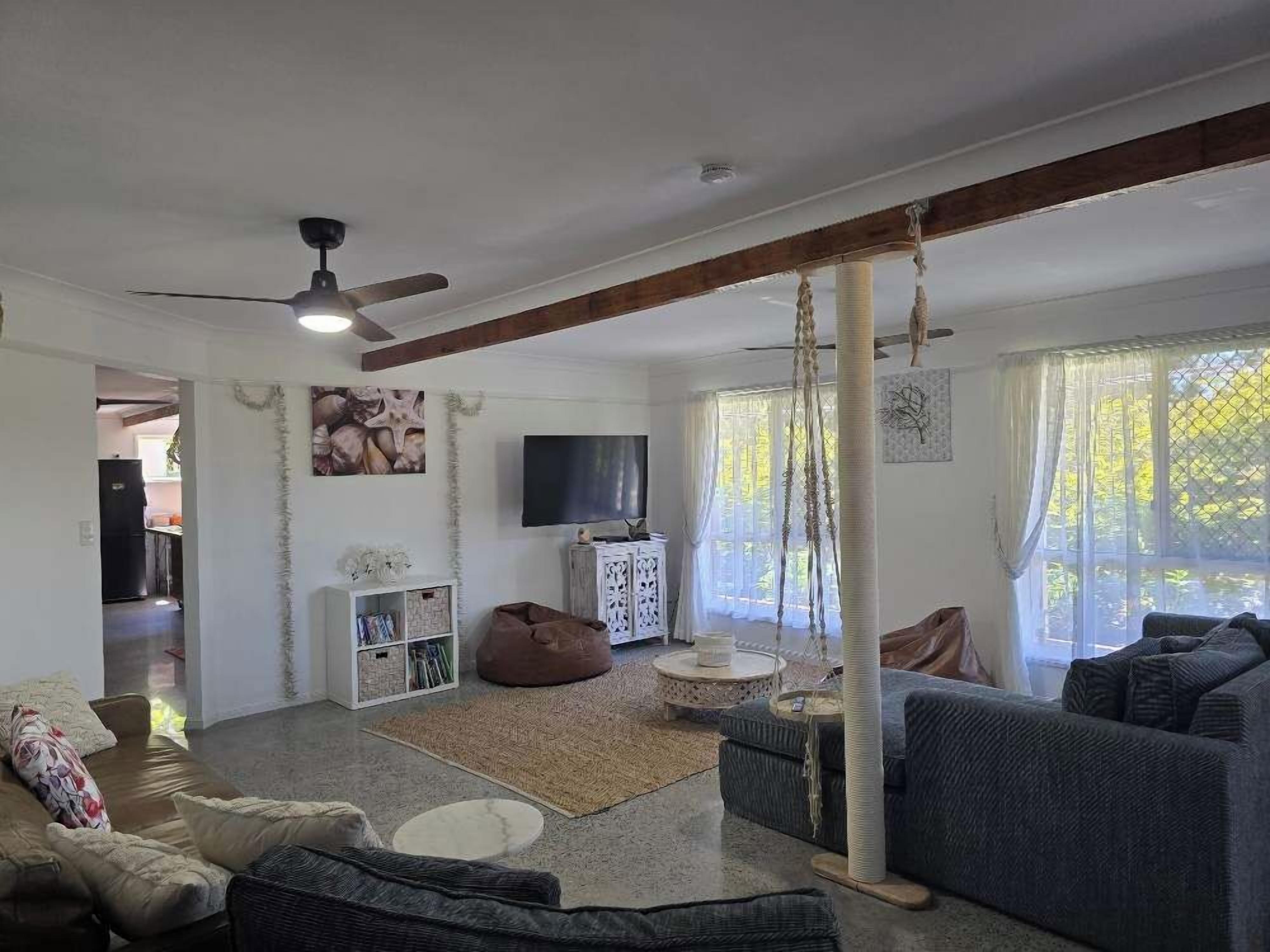 Una sala de estar con sofá, sillón de peluche, televisor y ventilador de techo.