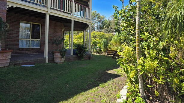 A two-story house with a balcony, surrounded by lush greenery and a well-maintained lawn. - SoKo Holiday Apartment (Agnes Water)