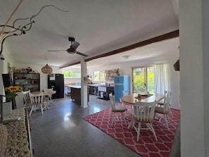A spacious kitchen with modern appliances, a dining area with white chairs, and a red patterned rug.