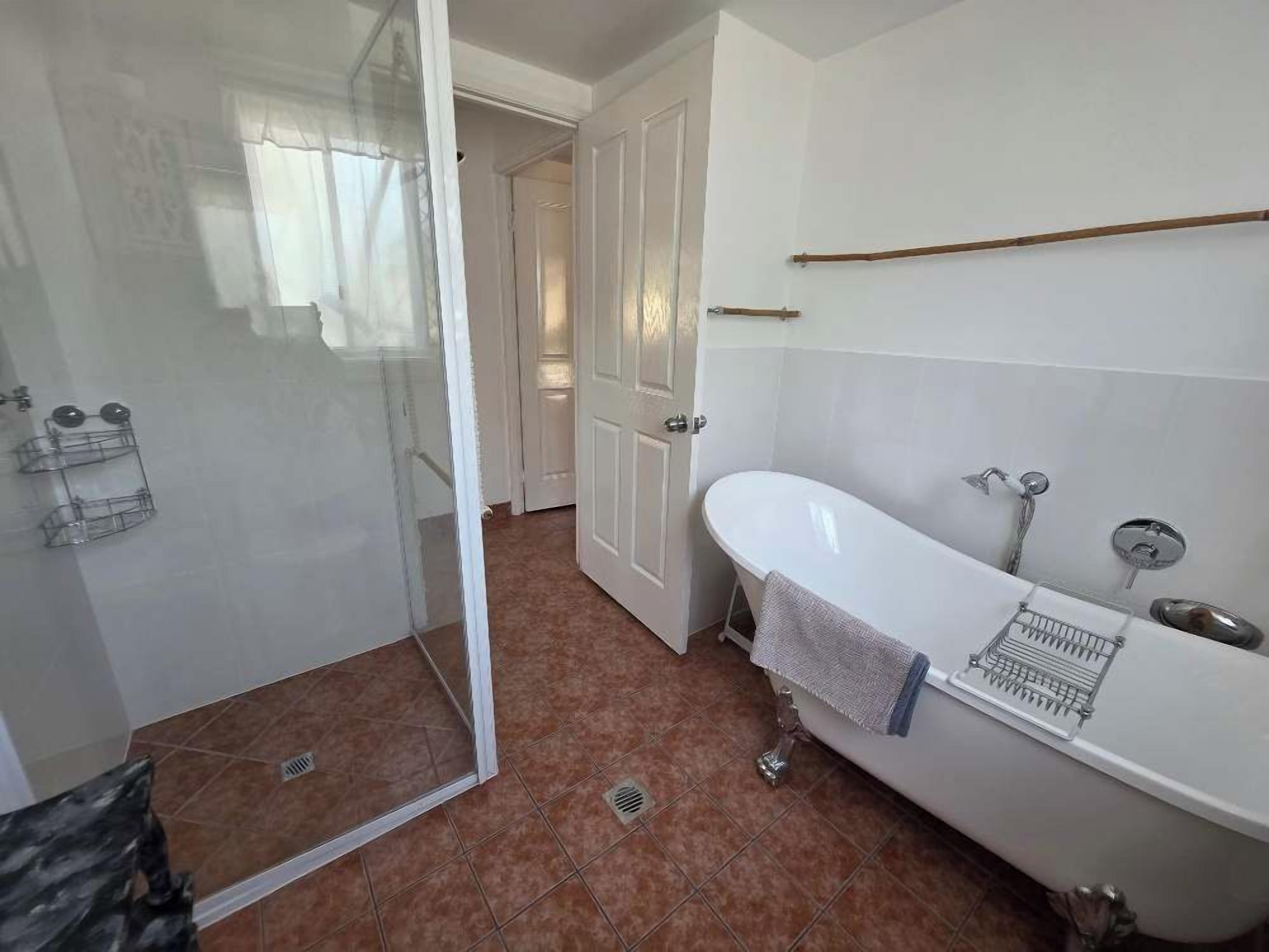 Ein Badezimmer mit einer weißen Badewanne, einer Duschkabine aus Glas und einem gefliesten Boden.