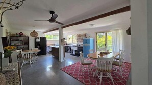A spacious kitchen with modern appliances, a dining area with white chairs, and a red patterned rug. - SoKo Holiday Apartment (Agnes Water)