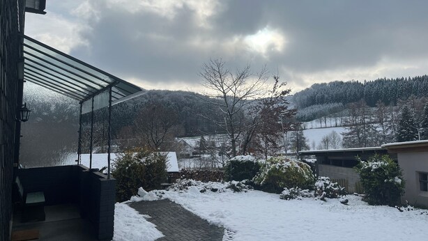 Un espacio al aire libre techado con vistas a colinas nevadas y un cielo nublado.