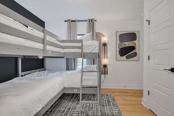 Une chambre avec un lit superposé, une échelle, un tapis à motifs et un luminaire fixé au mur.