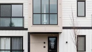 A modern multi-story building with a flat facade, large windows, and a visible entrance with a door number.
