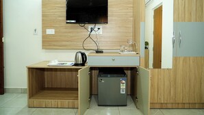 A compact kitchenette with a built-in TV, a small refrigerator, and a coffee maker. - Sweet Crystal Homes C V Raman Nagar (Bengaluru)