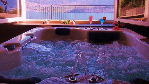 A hot tub with a view of mountains and a lake.