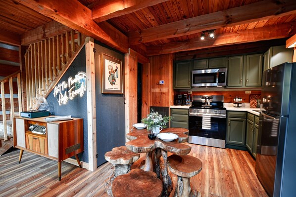 A rustic kitchen with wooden cabinetry, a built-in microwave, and a stainless steel refrigerator.