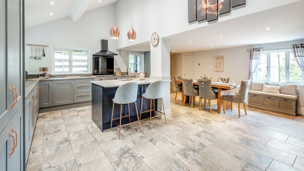 A spacious kitchen with a central island, modern pendant lights, and a dining area with a large table and chairs.