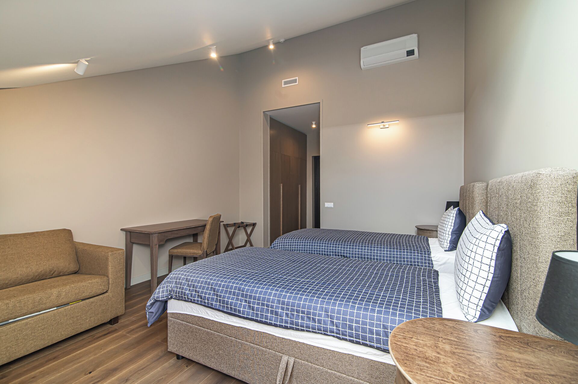 A bedroom with a bed, a chair, a desk, and a sofa.