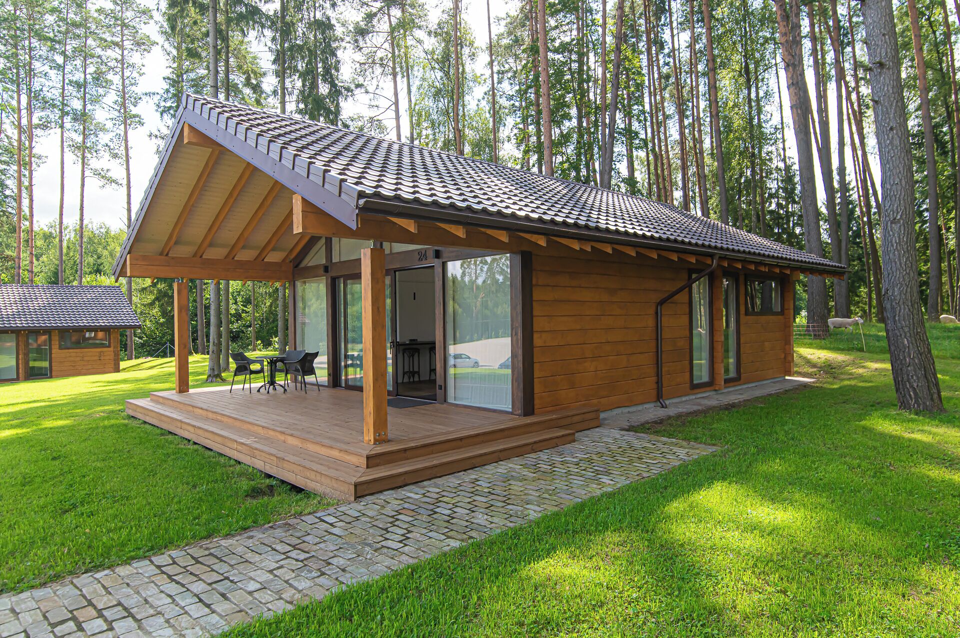 A wooden cabin with a tiled roof, a covered porch, and a stone pathway leading to it.
