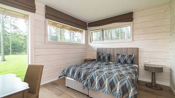 Un dormitorio con cama, una silla, una mesita de noche y una ventana.
