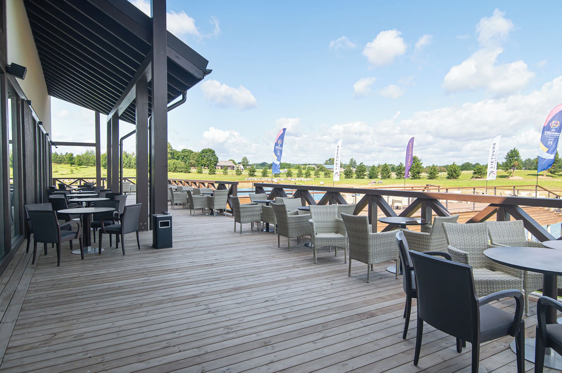 A covered outdoor seating area with tables and chairs, overlooking a golf course.