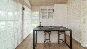Una cucina moderna con un piano di lavoro nero, due sgabelli e mobili bianchi.